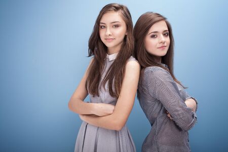 Beautiful young teenage girls posing on blue background in studio.の写真素材
