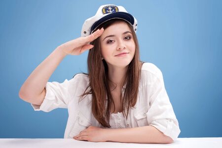 Smiling beautiful female sailor posing on blue background. Conceptual photo.の写真素材