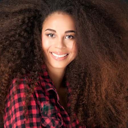 Portrait of smiling beautiful african american girl with long curly hair. Girl smiling. Student.