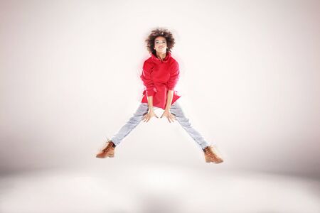 Young girl with afro jumping, flying, dancing in studio.