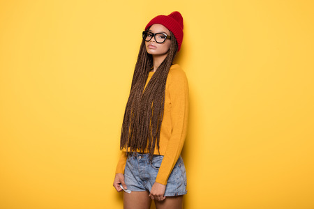 Fashionable young african american girl wearing red cap posing on yellow background.の写真素材