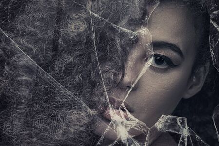 Beauty portrait of sensual african american woman with long curly hair , looking through broken...