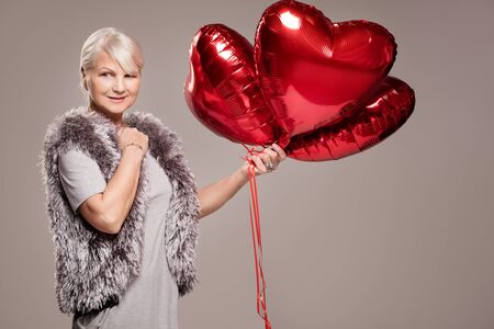 Elegant adult woman holding red balloons, valentine's day.の写真素材