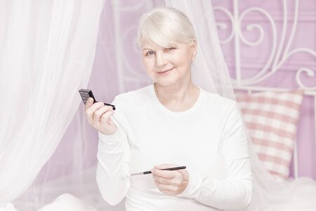 Beautiful senior woman doing makeup at the morning.の写真素材