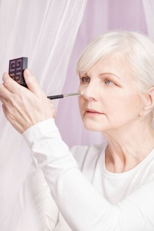 Beautiful senior woman doing makeup at the morning.の写真素材