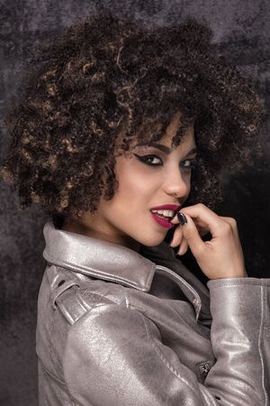 Fashionable young beautiful african american woman posing in silver jacket.の写真素材