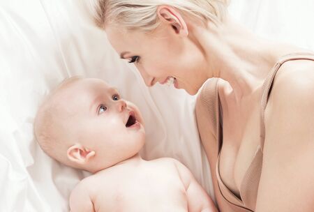 Beautiful mother posing with her little baby boy. Studio shot.