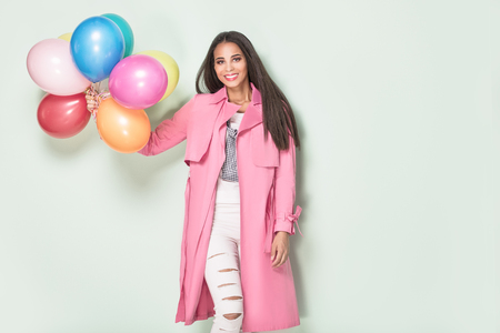 Happy beautiful african american woman holding colorful balloons, smiling to the camera.の写真素材