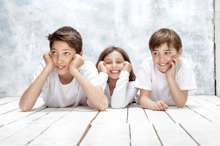 Happy three children posing together , wearing white shirts, smiling.の写真素材