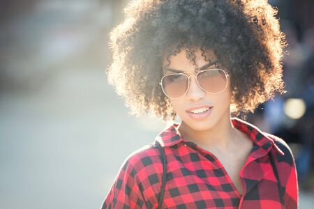 Fashionable young african american woman wearing sunglasses, urban scene.の写真素材
