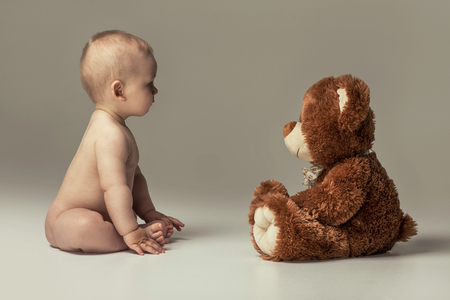 Little baby boy playing with his teddy bear in studio.の写真素材
