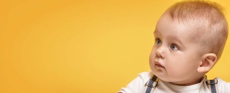 Cute baby boy posing on yellow background. Adorable little child in studio.の写真素材