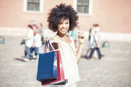 African american woman standing with shopping bags, smiling.の写真素材