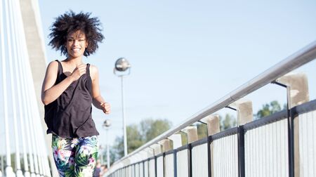 Photo of a young african american woman running outdoors.