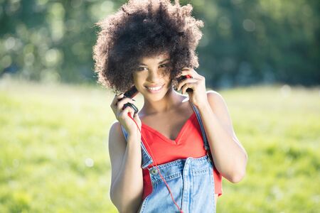 Photo of young african american girl with headphones, smiling. Outdoor photo.の写真素材