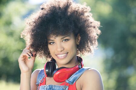 Photo of young african american girl with headphones, smiling. Outdoor photo.の写真素材
