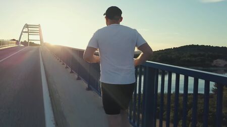 Male athlete training alone, running on the bridge in Croatia.の写真素材