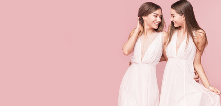Gorgeous two caucasian twins models posing together on pink pastel background, smiling.の写真素材