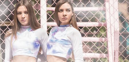 Two beautiful fashionable caucasian twins girls posing outdoor, summer sunny day.の写真素材