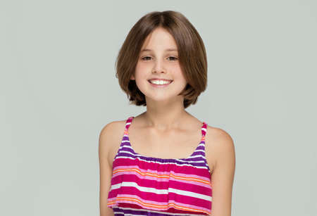Young beautiful girl posing in fashionable dress, smiling, looking at camera.