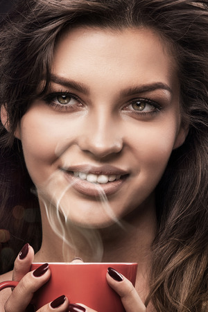 Portrait of beautiful brunette woman holding cup of coffee. Autumn mood.の写真素材