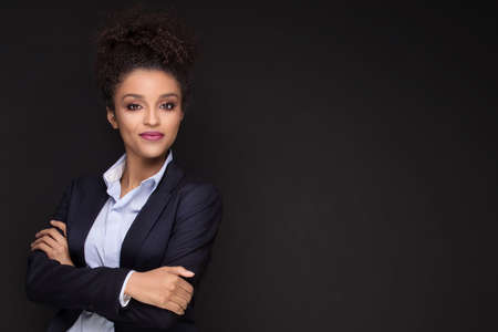 Photo of young african cheerful business woman standing over black background , smiling to the camera.Girl with afro hairstyle .の写真素材