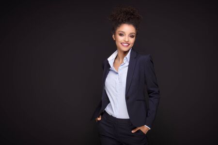 Photo of young african cheerful business woman standing over black background , smiling to the camera.Girl with afro hairstyle.の写真素材
