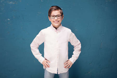 Kid in eyeglasses posing on blue background. Child Boy smiling, School Education concept.の写真素材