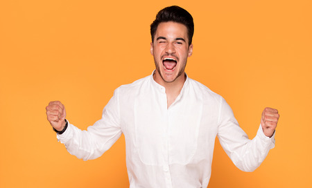 Photo of smiling handsome young man in elegant fashionable clothes on yellow studio background.