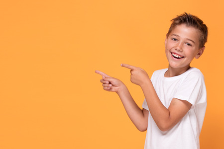 Young emotional handsome boy standing on orange studio background. Human emotions, facial expression...