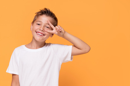 Young emotional handsome boy standing on orange studio background. Human emotions, facial expression concept.の写真素材