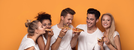 Group of multiracial friends eating pizza and having fun together.