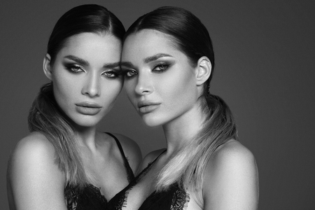 Beauty and femininity concept. Two attractive twins women in glamour makeup. Portrait photo.の写真素材