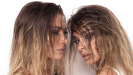 Beauty portrait of two attractive twins women in glamour makeup and wet long hair. Studio shot.の写真素材