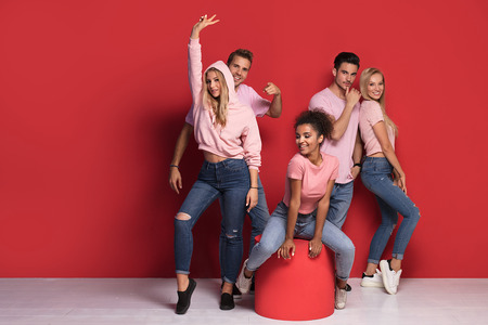 Group of young multi-ethnic attractive people smiling and having fun together, posing on colorful background in pink clothes.の写真素材
