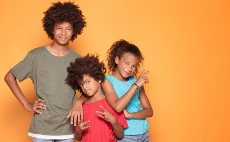 Happy smiling three afro children in colorful clothes posing together, smiling, having fun.の写真素材