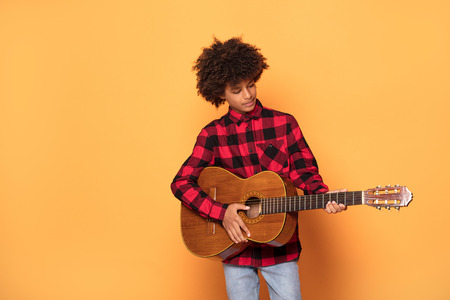 Studio shot of young African teenage boy posing with guitar.