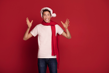 Happy teenager boy posing in Santa Claus hat, smiling, red studio background.の写真素材
