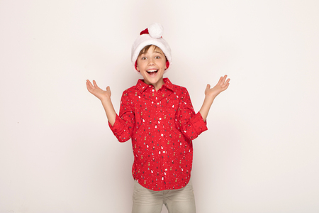 Funny smiling child boy in Santa red hat posing on white background.の写真素材