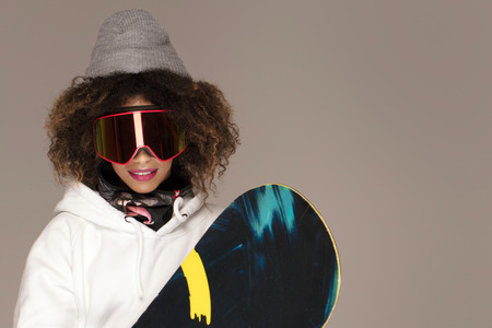 Gorgeous trendy afro woman with snowboard. Winter sport, hobby.の写真素材