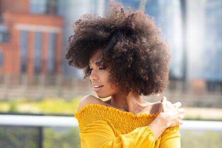 Portrait of young african american woman with curly hair posing in the city street.の写真素材