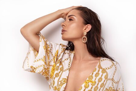 Fashion portrait of beautiful woman in elegant dress. Girl with gold jewelry. Glamour makeup.