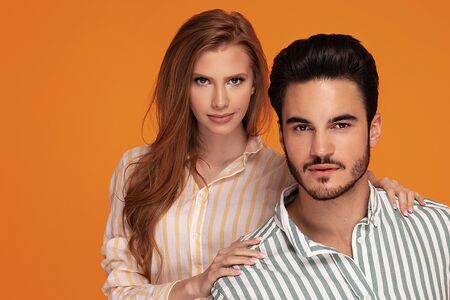Beautiful young couple posing together on yellow studio background. Facial expression, human...