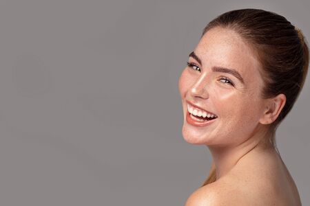 Beauty portrait of young attractive ginger woman with freckles on her face and body. Natural girl smiling to the camera. Studio shot.の写真素材