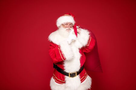 Photo of real Santa Claus with a huge red gift bag. Merry Christmas and Happy New Year concept.