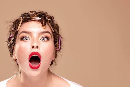 Beautiful shocked woman with rollers on head. Closeup beauty portrait of attractive girl with glamour face.の写真素材