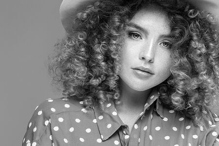 Portrait of beautiful woman with curly hairstyle and natural freckles. Girl looking at camera. Studio shot.の写真素材
