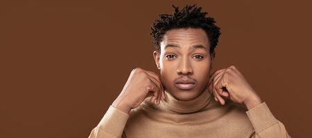 Closeup portrait of young african american man posing on brown studio background.