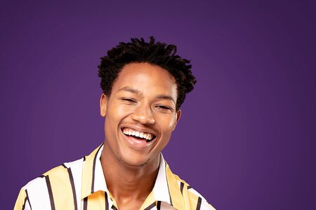 Happy african young man posing on purple studio background, smiling.の写真素材