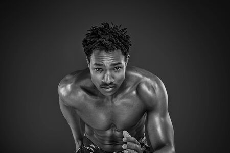 Young african man running in studio, looking at camera.の写真素材
